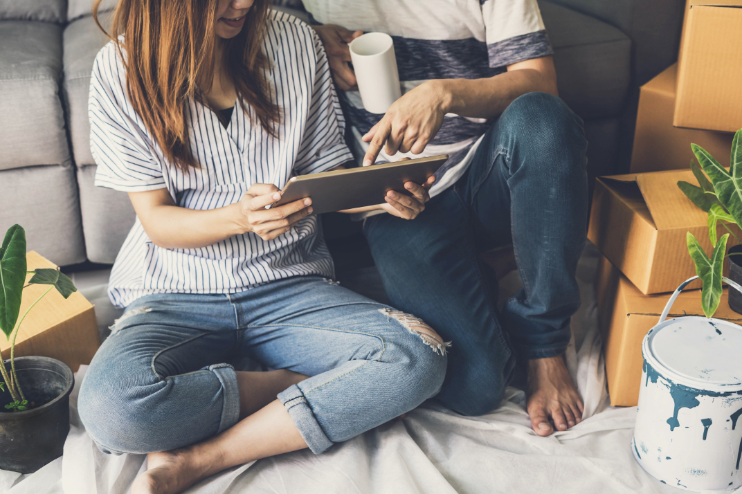 couple looking at an ipad in their home while drinking coffee